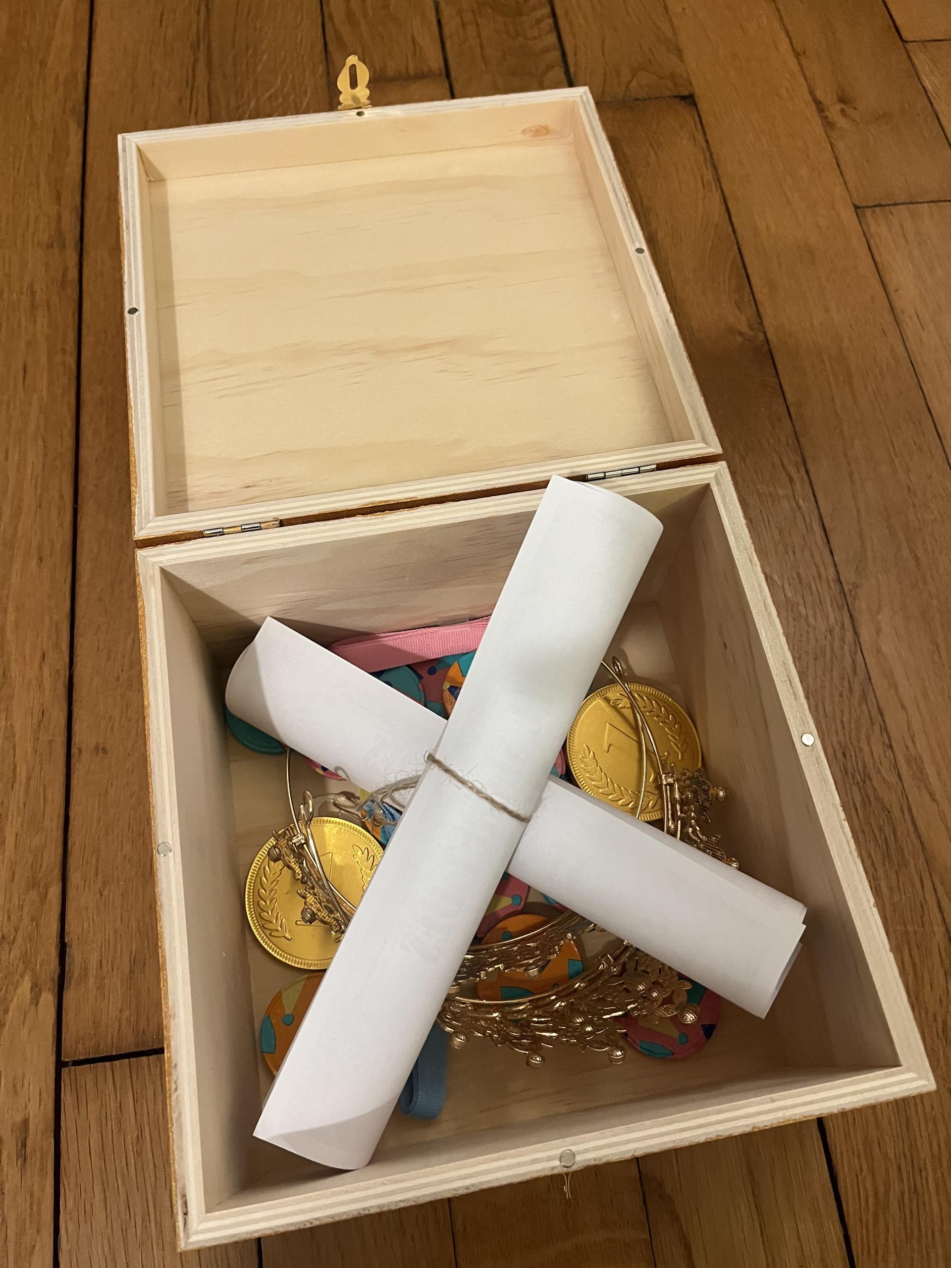 Open wooden treasure box with medals, ribbons, and scrolls